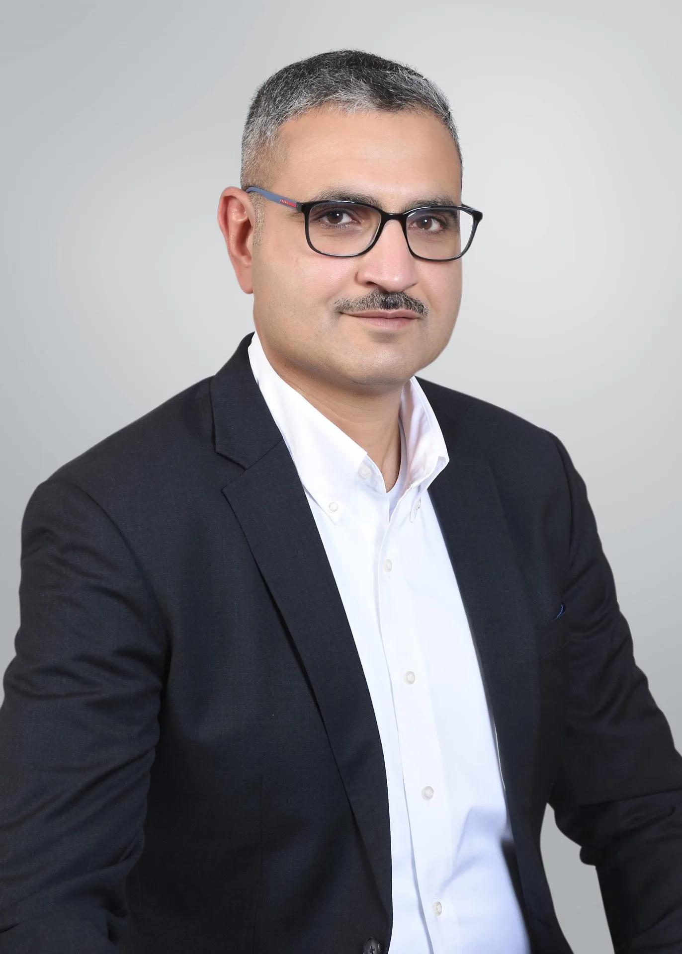 Professional headshot of Jasim Alulaiw against a plain gray background.